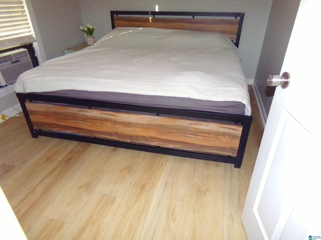 bedroom featuring cooling unit, wood finished floors, and baseboards