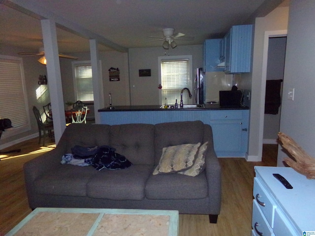 living area featuring light wood-style flooring, baseboards, and a ceiling fan