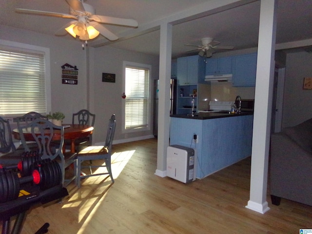 kitchen featuring a ceiling fan, light wood-style floors, dark countertops, freestanding refrigerator, and under cabinet range hood