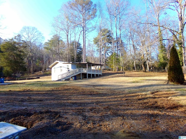 view of yard with a wooden deck and a view of trees