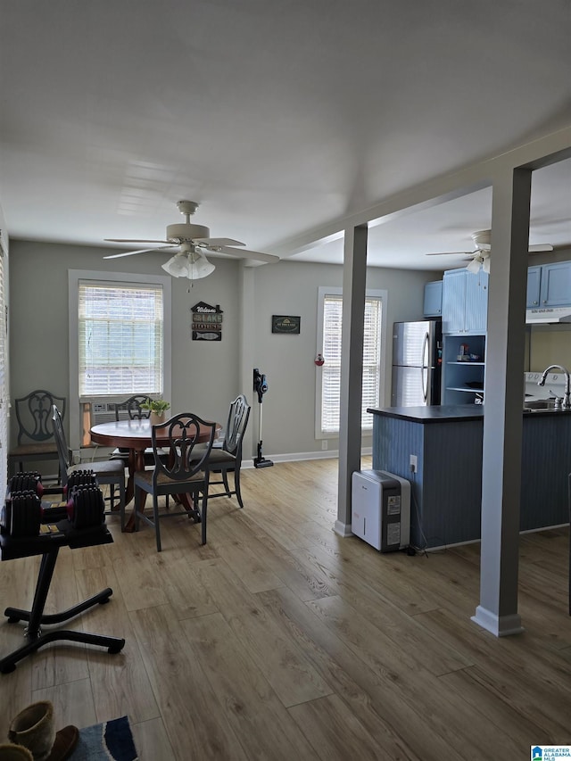 dining room with a ceiling fan, a healthy amount of sunlight, baseboards, and wood finished floors