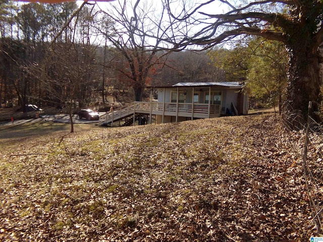 exterior space with metal roof, a wooded view, and a wooden deck