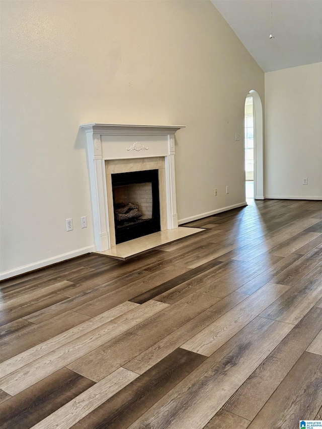 unfurnished living room featuring hardwood / wood-style flooring, high vaulted ceiling, and a fireplace