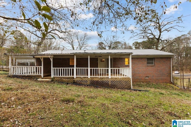 rear view of property featuring covered porch and a lawn