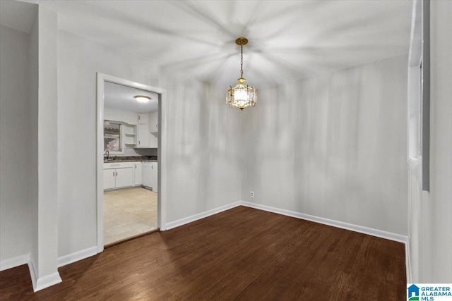 spare room featuring dark hardwood / wood-style flooring, sink, and a notable chandelier