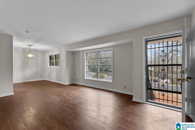 spare room with an inviting chandelier and dark hardwood / wood-style floors