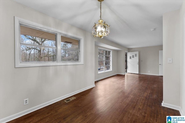 empty room featuring dark wood-type flooring and a notable chandelier