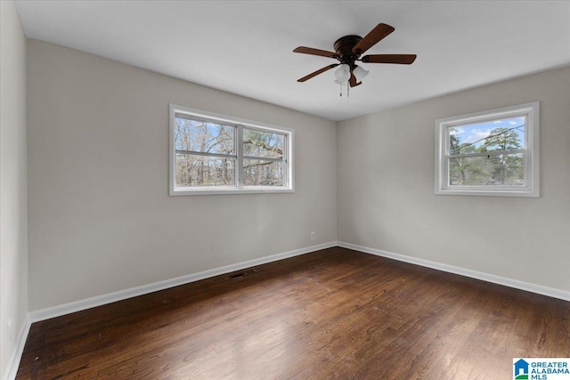 unfurnished room featuring ceiling fan, dark wood-type flooring, and a healthy amount of sunlight