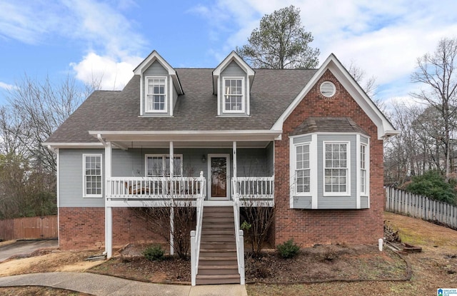 view of front of property featuring fence, covered porch, a shingled roof, stairs, and brick siding