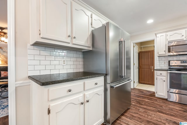 kitchen with backsplash, appliances with stainless steel finishes, dark wood-type flooring, and white cabinets