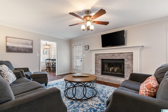 living room featuring hardwood / wood-style flooring, ceiling fan, ornamental molding, a textured ceiling, and a brick fireplace