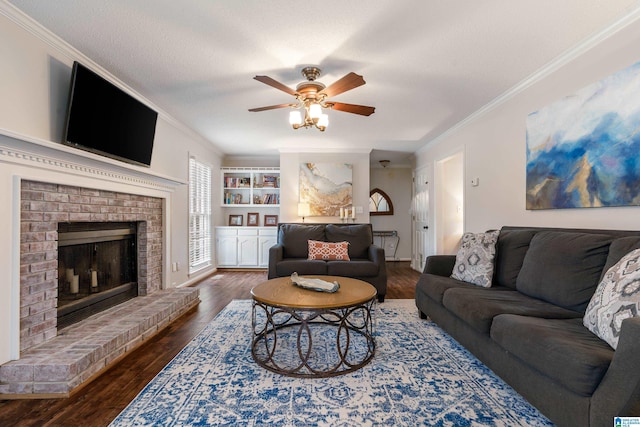 living room featuring ceiling fan, hardwood / wood-style floors, a fireplace, ornamental molding, and a textured ceiling