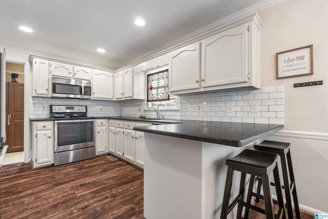 kitchen featuring stainless steel appliances, a breakfast bar, white cabinets, and kitchen peninsula