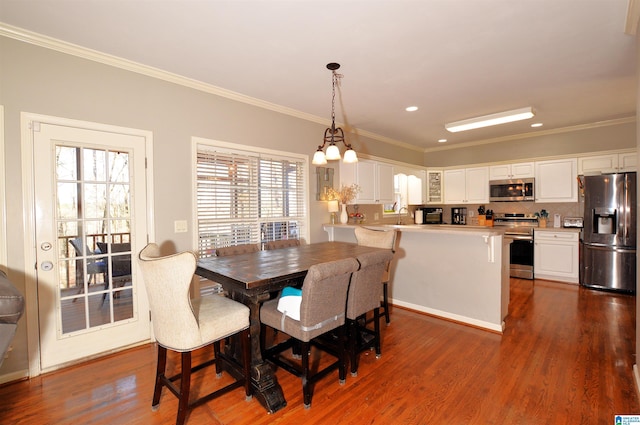 dining area with sink, dark wood-type flooring, ornamental molding, and plenty of natural light