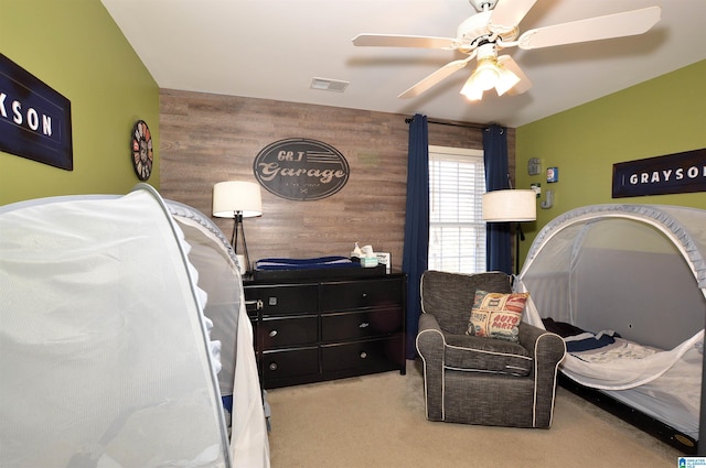 bedroom featuring light carpet, wooden walls, and ceiling fan