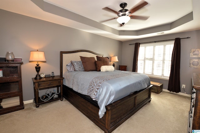 carpeted bedroom featuring a raised ceiling and ceiling fan