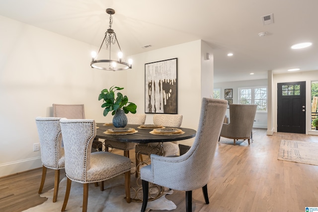 dining space with a notable chandelier and light hardwood / wood-style flooring