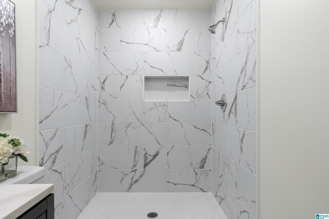 bathroom featuring tiled shower and vanity