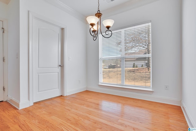 empty room with ornamental molding, a chandelier, and light wood-type flooring