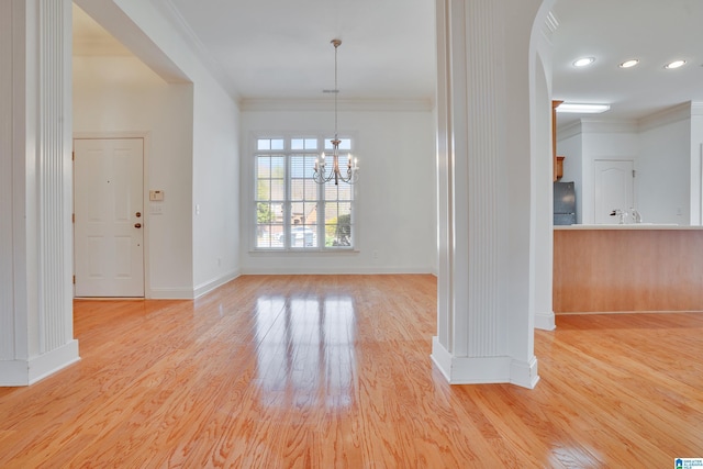 unfurnished dining area with crown molding, an inviting chandelier, and light wood-type flooring