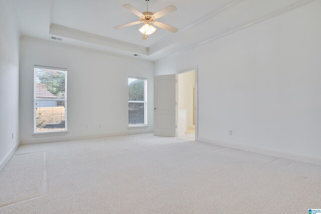 carpeted spare room featuring a tray ceiling, ornamental molding, and ceiling fan