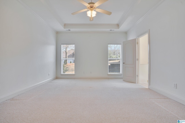 carpeted empty room with plenty of natural light, a raised ceiling, and ceiling fan