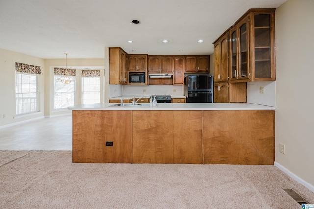 kitchen featuring sink, light carpet, hanging light fixtures, kitchen peninsula, and black appliances