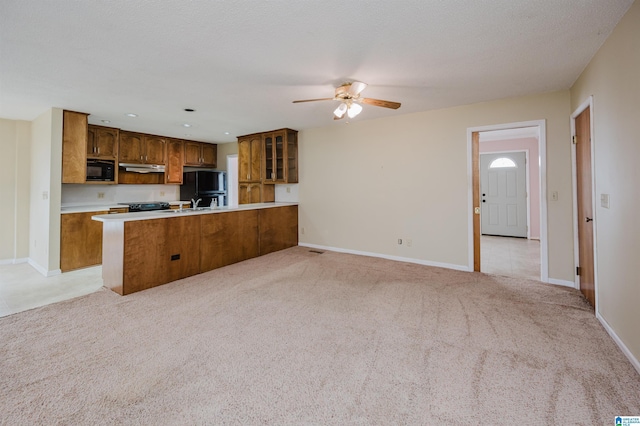 kitchen with sink, light colored carpet, kitchen peninsula, ceiling fan, and black appliances