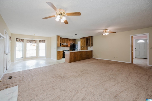 unfurnished living room with light colored carpet, ceiling fan with notable chandelier, and a textured ceiling