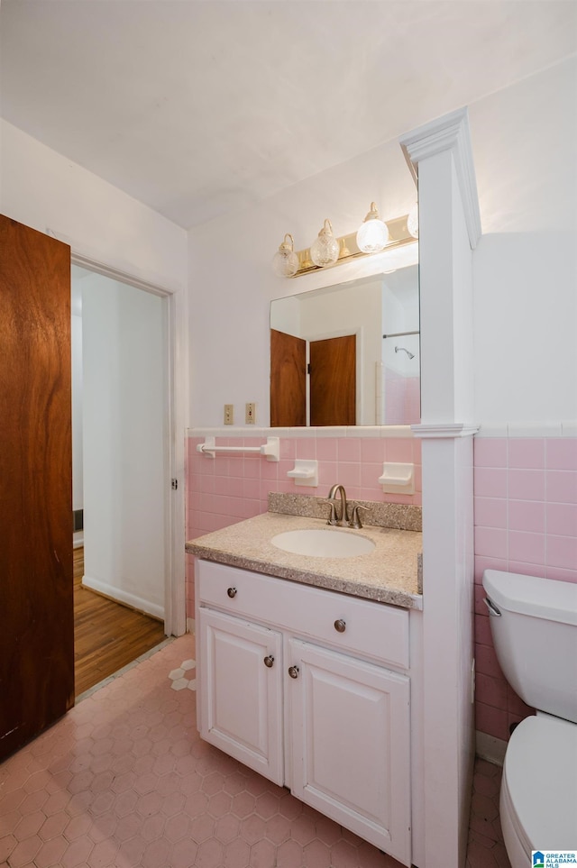 bathroom featuring vanity, toilet, and tile walls