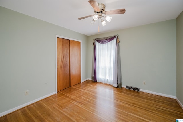 unfurnished bedroom featuring hardwood / wood-style floors, ceiling fan, and a closet