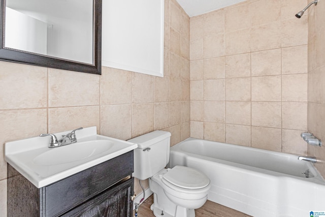 full bathroom featuring tiled shower / bath, tile walls, hardwood / wood-style flooring, vanity, and toilet