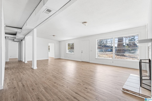 unfurnished living room featuring a textured ceiling and light hardwood / wood-style flooring