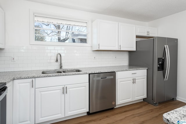 kitchen featuring light stone counters, stainless steel appliances, sink, and white cabinets