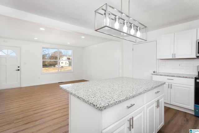 kitchen with white cabinetry, a kitchen island, pendant lighting, and backsplash