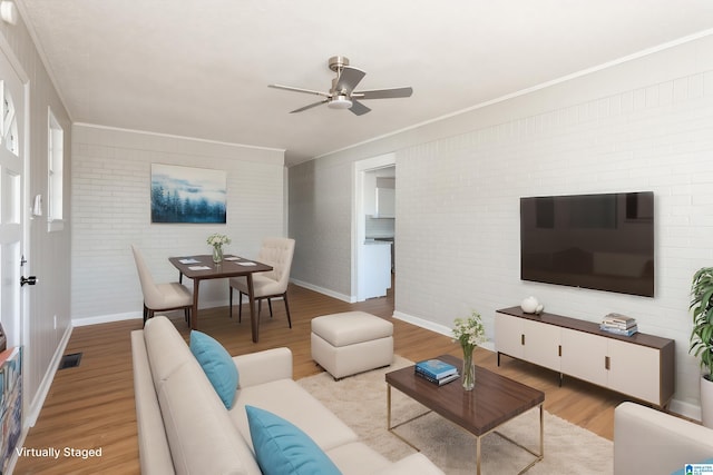 living room featuring ornamental molding, brick wall, ceiling fan, and light hardwood / wood-style flooring