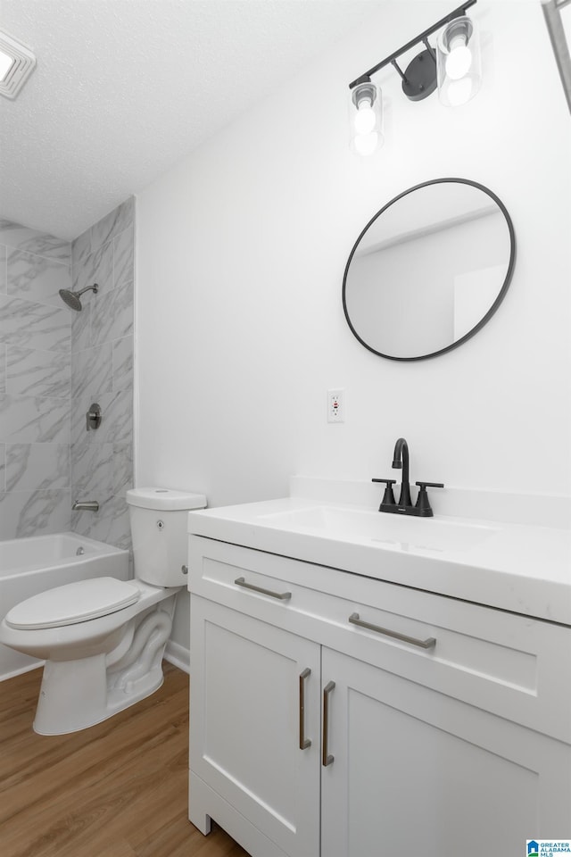 full bathroom featuring hardwood / wood-style flooring, vanity, a textured ceiling, toilet, and tiled shower / bath