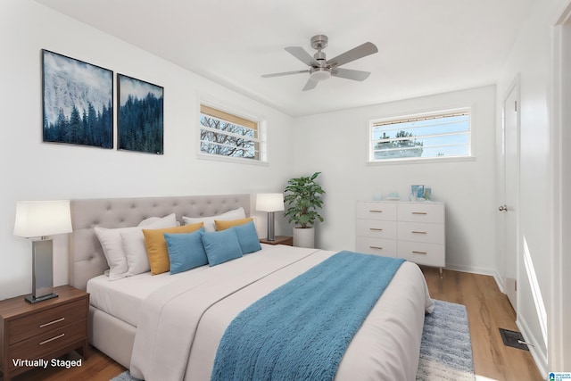 bedroom featuring multiple windows, hardwood / wood-style floors, and ceiling fan