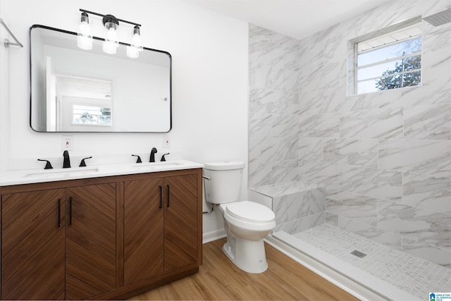 bathroom featuring hardwood / wood-style flooring, vanity, toilet, and a tile shower