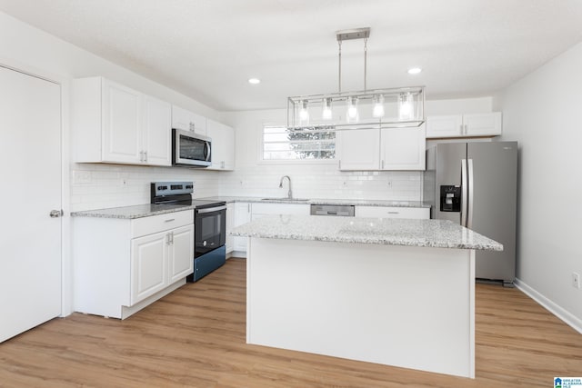 kitchen with white cabinetry, hanging light fixtures, a kitchen island, and appliances with stainless steel finishes