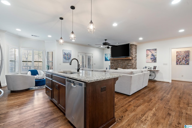 kitchen featuring sink, hanging light fixtures, stainless steel dishwasher, an island with sink, and light stone countertops