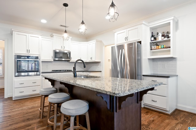 kitchen featuring light stone counters, white cabinetry, stainless steel appliances, and decorative light fixtures