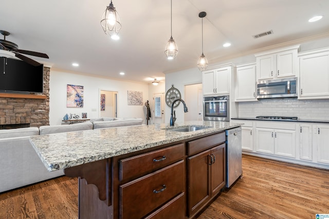 kitchen with pendant lighting, sink, appliances with stainless steel finishes, light stone counters, and white cabinets