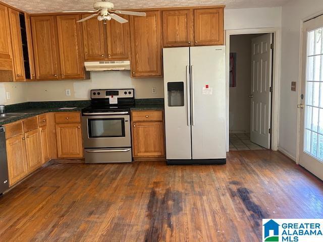 kitchen with sink, a textured ceiling, appliances with stainless steel finishes, dark hardwood / wood-style floors, and ceiling fan