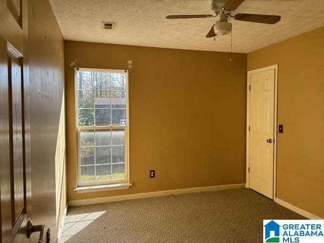 carpeted spare room with ceiling fan and a textured ceiling