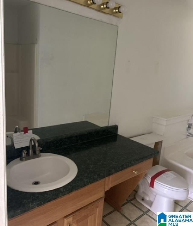 bathroom featuring vanity, tile patterned floors, a tub, and toilet