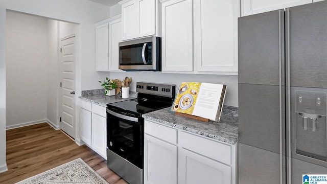 kitchen featuring appliances with stainless steel finishes, light stone counters, white cabinets, and dark hardwood / wood-style flooring