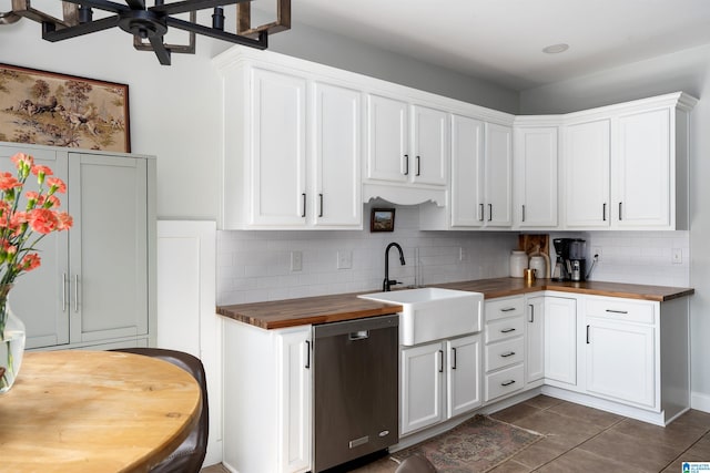 kitchen with wood counters, sink, tasteful backsplash, stainless steel dishwasher, and white cabinets