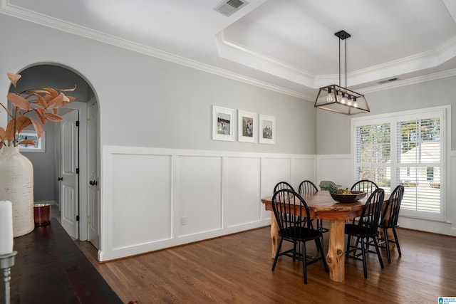 dining room featuring crown molding, a tray ceiling, and dark wood-type flooring