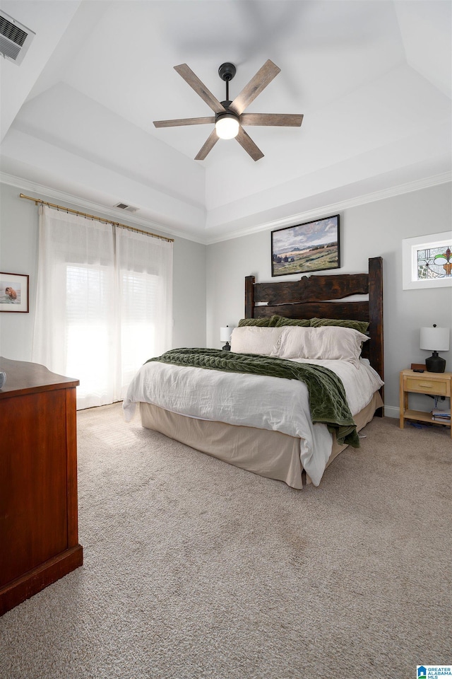 carpeted bedroom featuring a raised ceiling, crown molding, and ceiling fan